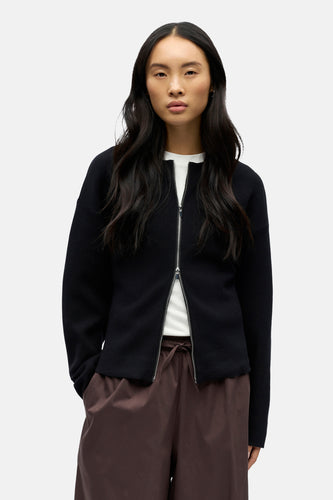 Vrouw in zwart vest en bruine broek.