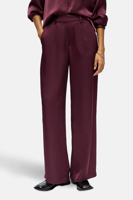 Pantalon noir d'OBJECT, avec des jambes larges et porté avec une blouse coordonnée et des chaussures noires.