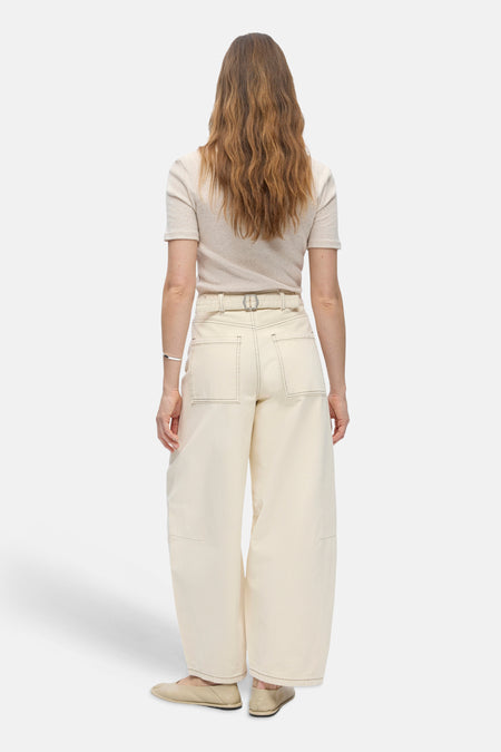Jean beige coupe spéciale de OBJECT, dos, jambes larges, coutures contrastées, haut clair, bracelet argenté et chaussures plates.