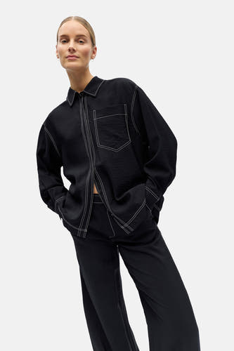 Chemise noire à manches longues de OBJECT, finie avec des surpiqûres blanches, portée avec un pantalon assorti.