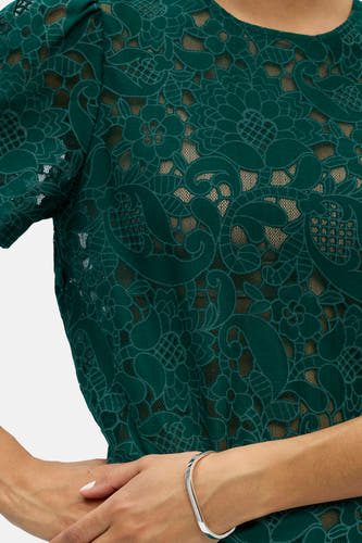 Haut vert à manches courtes de OBJECT, en dentelle à motifs floraux et cachemire, avec un bracelet argenté.