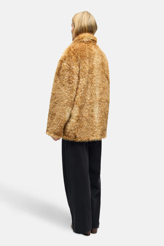 Manteau court brun d'OBJECT, avec une texture fausse fourrure et porté avec un pantalon noir.