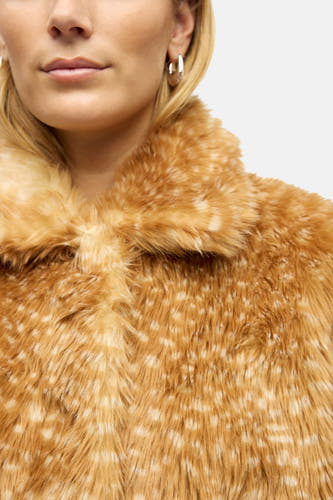 Manteau court brun d'OBJECT avec une texture de fourrure douce et des légères taches, porté avec des boucles d'oreilles en argent.