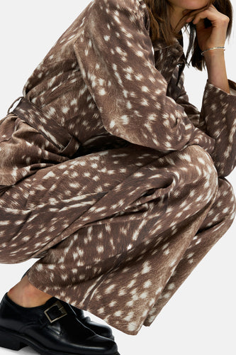 Een vrouw in een bruine jumpsuit met een hertengeweermotief.