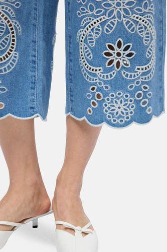 Short en jean bleu clair de OBJECT avec broderie blanche, motif ajouré et ourlet festonné, porté avec des mules blanches.