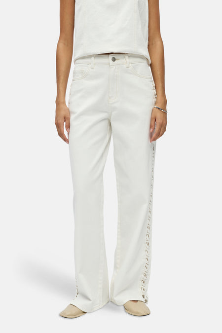 Jean blanc d'OBJECT avec détails découpés sur les côtés, stylisé avec un haut blanc, un bracelet argenté et des mules beiges.