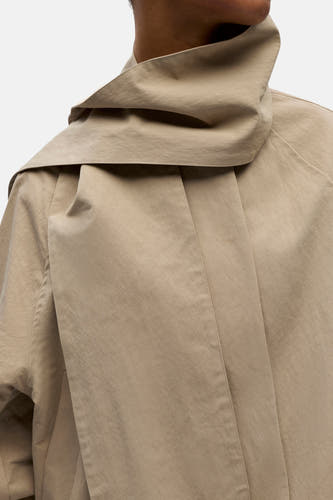 Manteau court beige d'OBJECT, avec un col large et des plis dans le dos.
