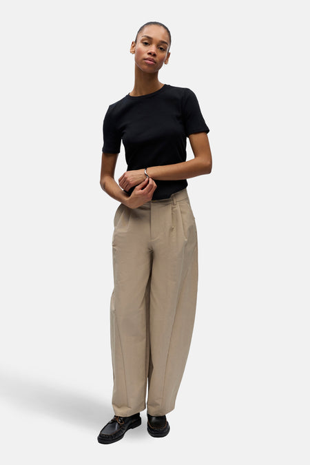 Pantalon beige de OBJECT, avec plis et jambes larges, combiné avec un t-shirt noir et des chaussures noires.