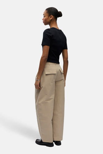Pantalon beige de OBJECT, avec jambes larges et poches arrière, porté avec un t-shirt noir et des chaussures noires.