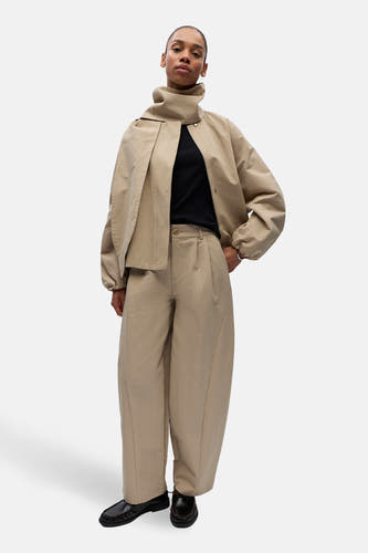 Pantalon beige de OBJECT, avec plis, jambes larges et porté avec un haut noir et des chaussures noires.
