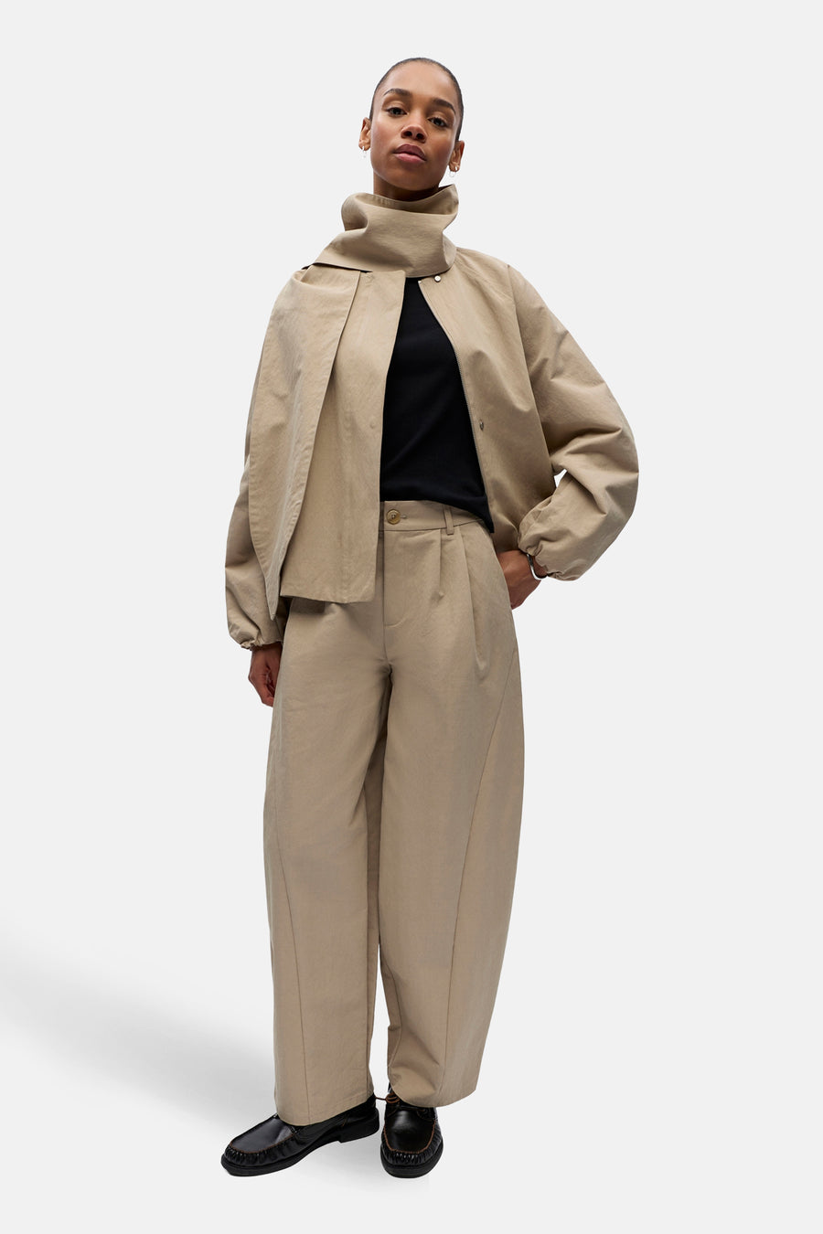 Pantalon beige de OBJECT, avec plis, jambes larges et porté avec un haut noir et des chaussures noires.