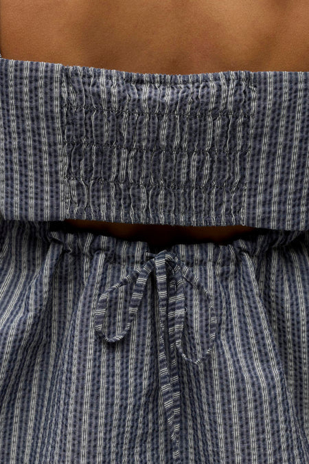 Chemisier sans manches bleu d'OBJECT avec un motif rayé et à carreaux, accentué par une taille smockée et un détail de nœud.