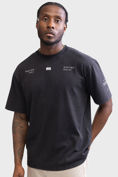 T-shirt noir à manches courtes de REDEFINED REBEL, avec du texte blanc sur la poitrine et une tatouage sur le bras gauche.