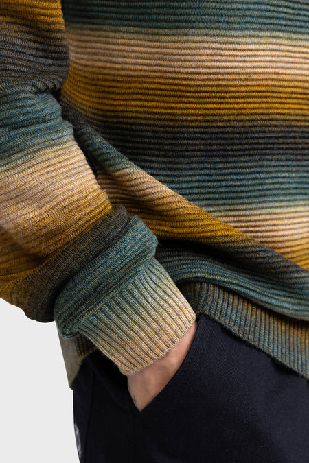 Pull-over marron avec col rond de REDEFINED REBEL, rayé en or et en vert, avec un homme en pantalon foncé.