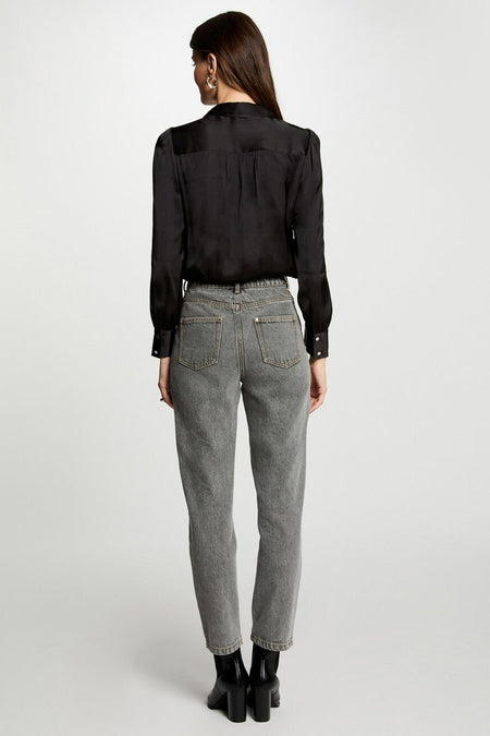 Chemise noire en satin à manches longues de Morgan De Toi, dos plissé, portée avec un jean gris et des bottes noires