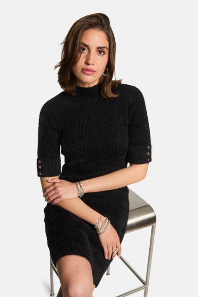 Robe noire à manches courtes de Morgan De Toi, avec des boutons d'or sur les manches et des bracelets d'argent.