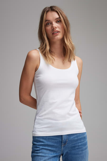 T-shirt blanc d'OPUS, porté avec un jean, les mains derrière le dos.