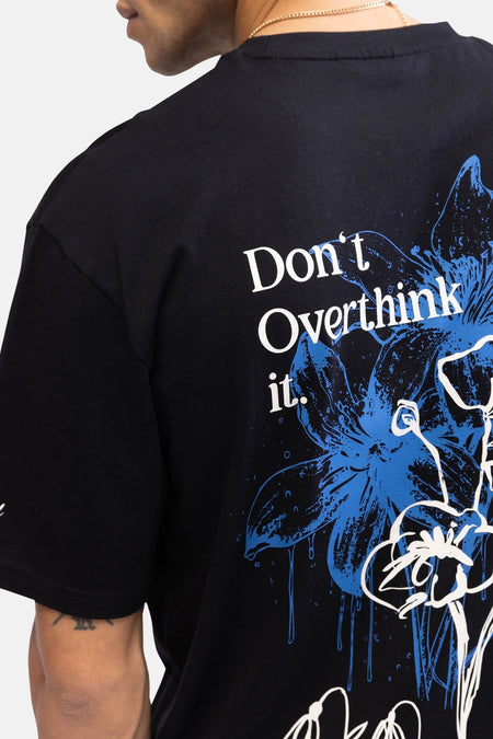 T-shirt noir à manches courtes de REDEFINED REBEL, avec imprimé de fleurs et le texte "Don't Overthink it." sur le dos.