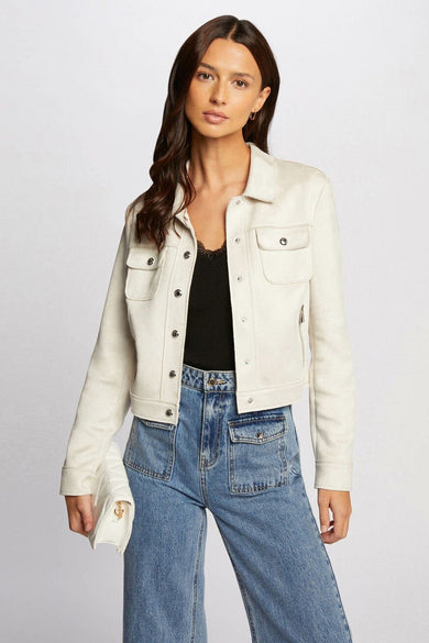 Manteau court beige de Morgan De Toi, avec une fermeture éclair argentée, porté avec des jeans larges et des loafers blancs.