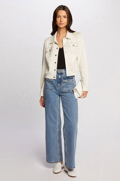 Manteau court beige de Morgan De Toi, porté avec un haut noir, des jeans bleus à poches et des loafers blancs.