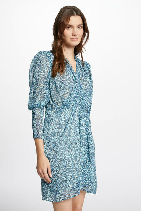 Jupe courte bleue de Morgan De Toi, avec des manches longues et un motif floral, associée à des bottes crème.