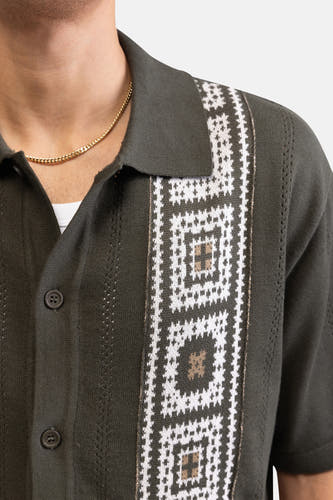 Chemise tricotée verte à manches courtes de REDEFINED REBEL avec motif géométrique blanc et beige, col polo et chaîne dorée.