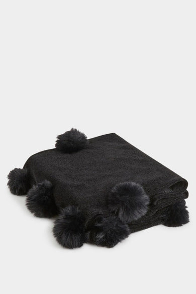 Chapeau d'hiver noir de Morgan de Toi avec des pompons doux sur les bords, sur un fond lisse.