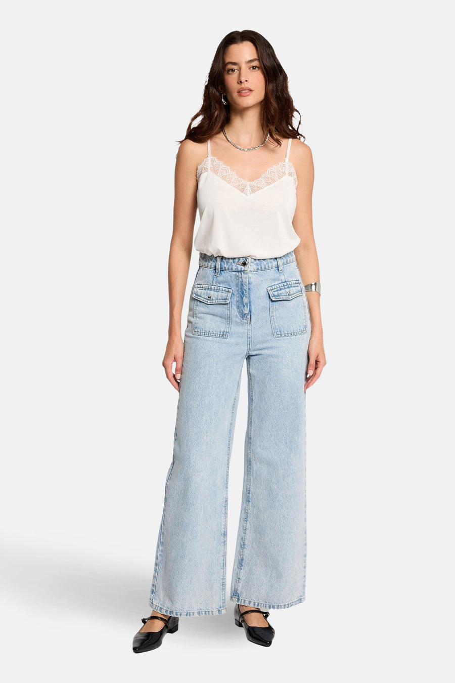 Haut blanc à fines bretelles de Morgan De Toi, fini avec des détails en dentelle autour de l'encolure, combiné avec un jean ample.