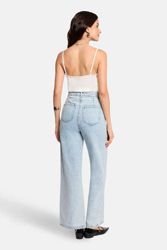 Witte top met spaghettibandjes van Morgan De Toi, gezien van achteren, met zilveren sieraden en wijde jeans.