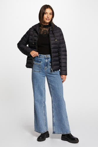 Manteau court noir de Morgan De Toi, avec une capuche, porté avec un haut noir et des jeans larges.
