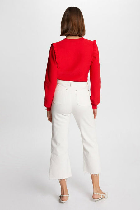 Pull rouge à col rond de Morgan De Toi, avec des volants sur les épaules, associé à des jeans blancs.