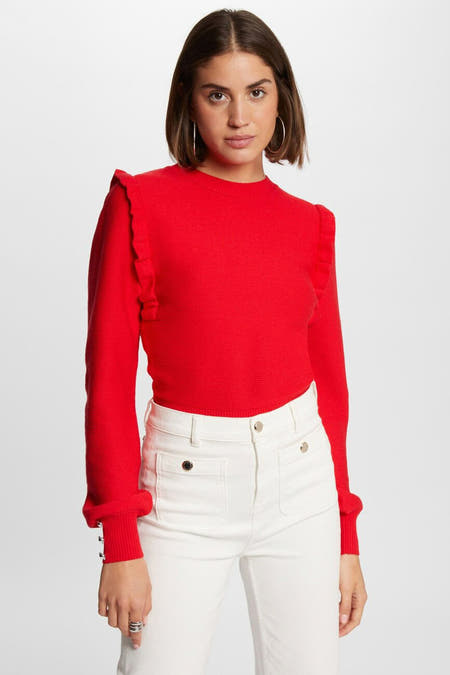 T-shirt rouge à col rond de Morgan De Toi, avec longues manches et volants sur les épaules, porté avec un pantalon blanc.