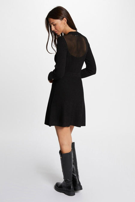 Robe noire à longues manches de Morgan De Toi, avec des détails rayés sur le dos, portée avec des bottes noires.