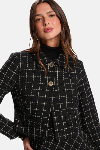 Manteau court noir de Morgan De Toi avec motif à carreaux, porté avec une jupe et des loafers en cuir noir.