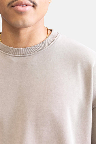 Beige trui met gouden ketting.
