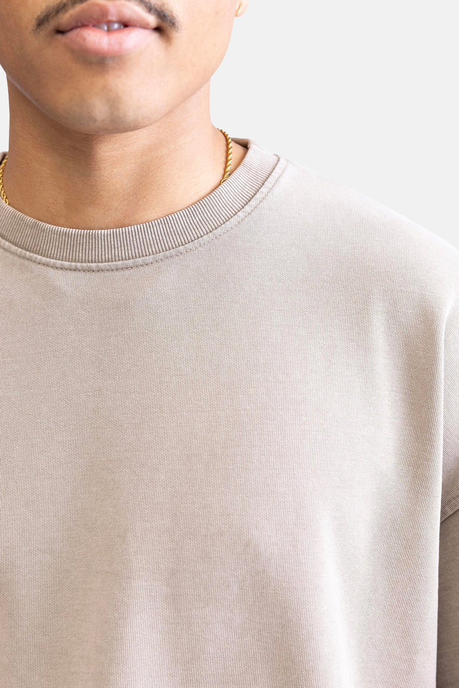 Beige trui met gouden ketting.
