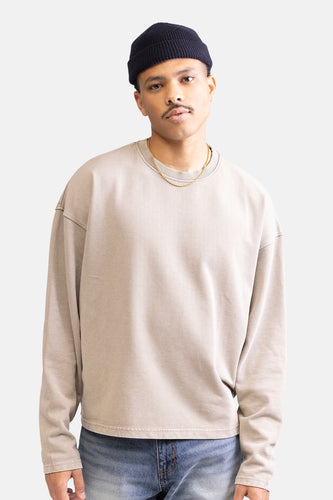 Man met muts, beige sweater en gouden ketting.