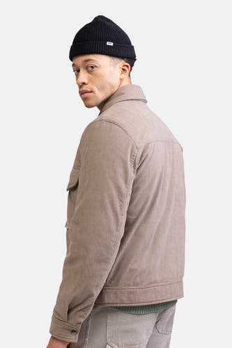 Manteau court beige de REDEFINED REBEL, en tissu corduroy, porté avec un bonnet noir.