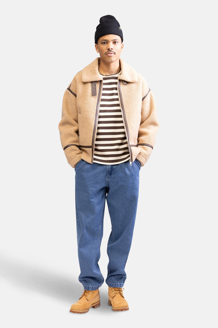 Beige, short jacket from REDEFINED REBEL, with brown accents, worn with a striped top, jeans and suede boots.
