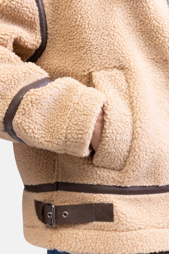 Manteau court beige de REDEFINED REBEL avec des détails marrons et une main dans la poche.