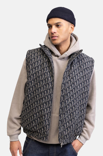 Gilet multicolore de REDEFINED REBEL, avec un motif bleu foncé et beige, porté sur une hoodie grise et un bonnet bleu foncé.