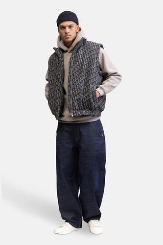 Gilet multicolore de REDEFINED REBEL, avec un motif all-over, porté sur une hoodie grise et des jeans larges et sombres.