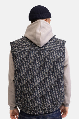 Multicolor bodywarmer van REDEFINED REBEL, met een donkerblauwe en beige patroon, gedragen over een grijze hoodie en een donkerblauwe muts.