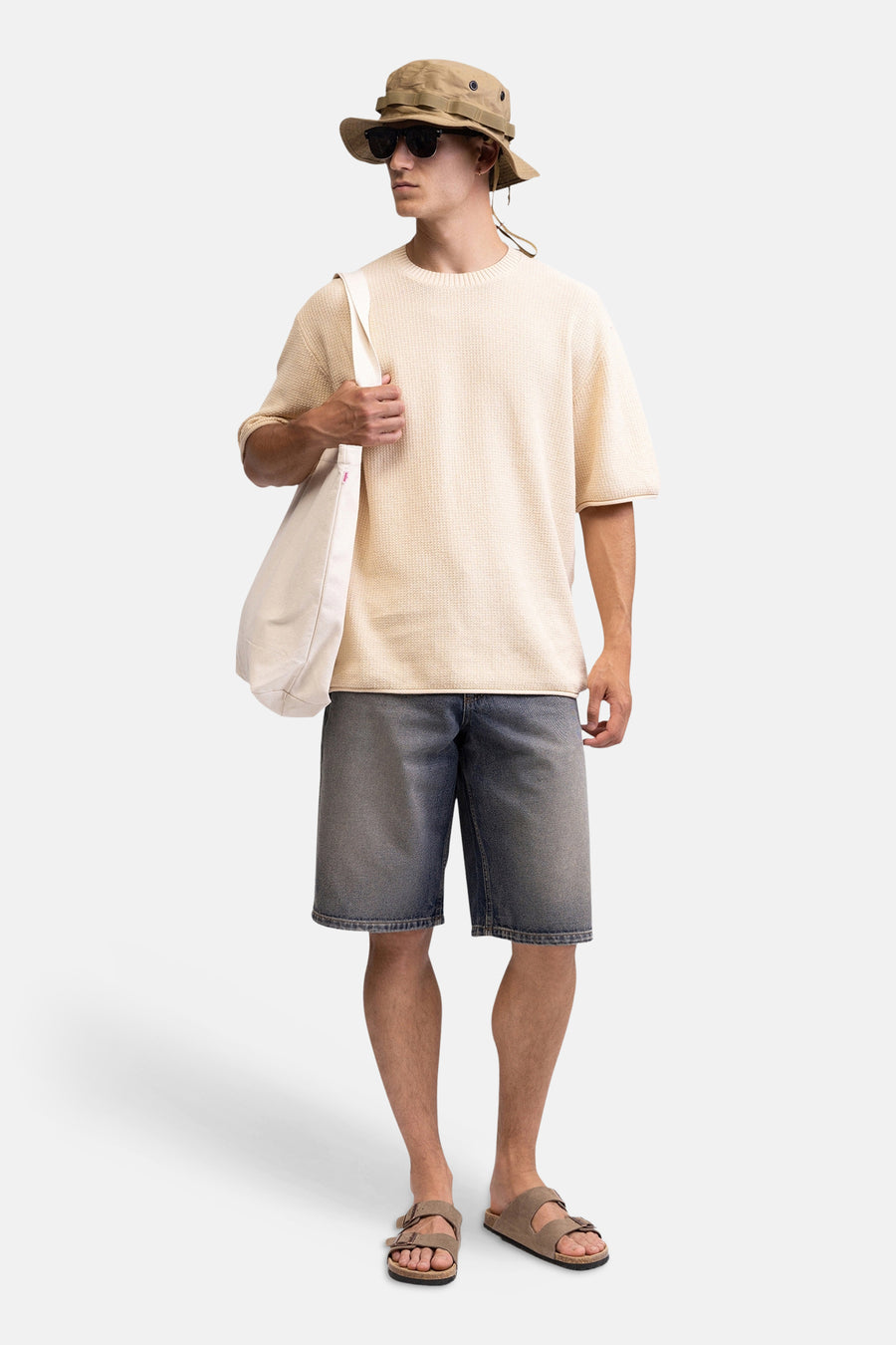 Mid-length blauwe denim shorts van REDEFINED REBEL, gedragen met een beige trui, bucket hat en sandalen, lifestyle shot.