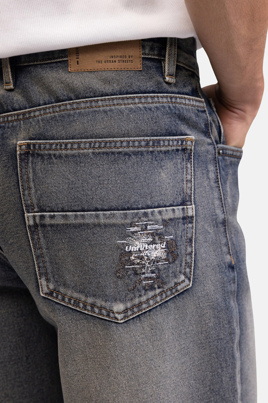 Blauwe denim jeansshorts van REDEFINED REBEL, achterzijde met geborduurd logo en verweerd look, close-up.