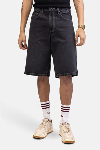 Jean short gris foncé de REDEFINED REBEL, avec des surpiqures contrastantes, associé à des collants et des baskets beige.