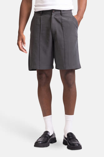 Short gris de REDEFINED REBEL, avec des plis, associé à un T-shirt blanc, des chaussettes blanches et des loafers noirs.