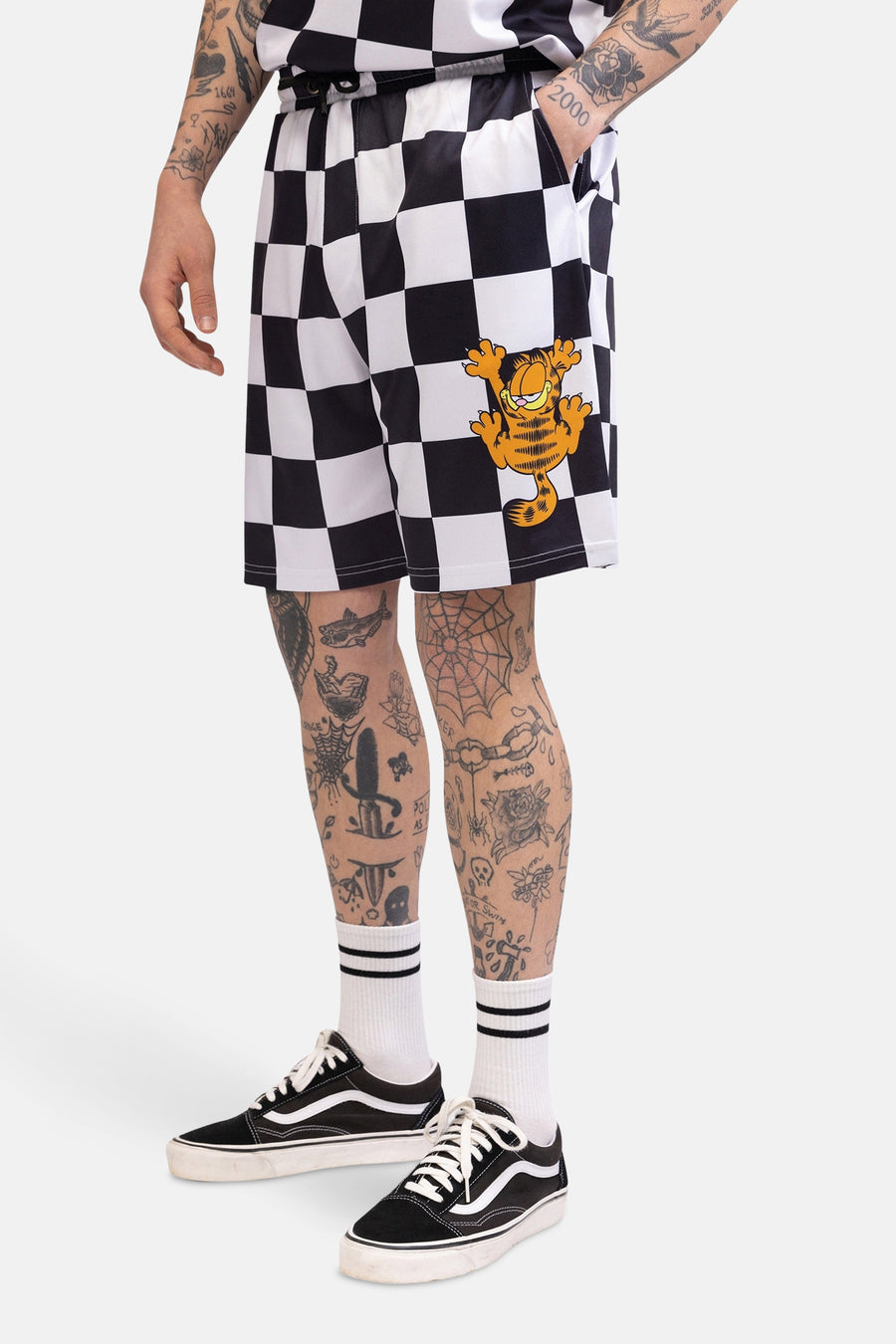Shorts noirs et blancs à motif damier de CULT, avec des chaussettes rayées et des chaussures noires.