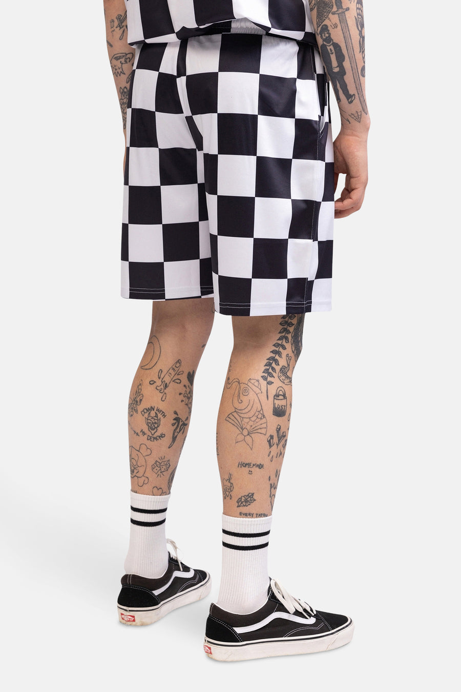 Zwarte en witte shorts met dambordpatroon van CULT, met sokken met strepen en zwarte schoenen.