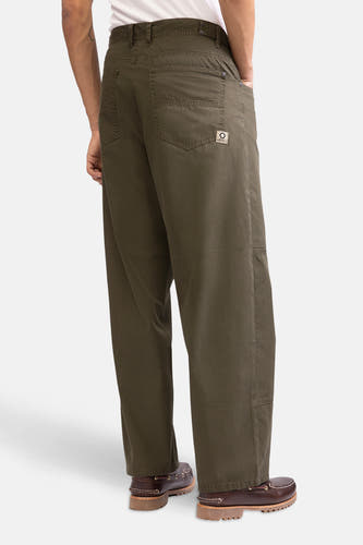 Pantalon vert de REDEFINED REBEL, avec des poches arrière, porté avec des chaussures marron.